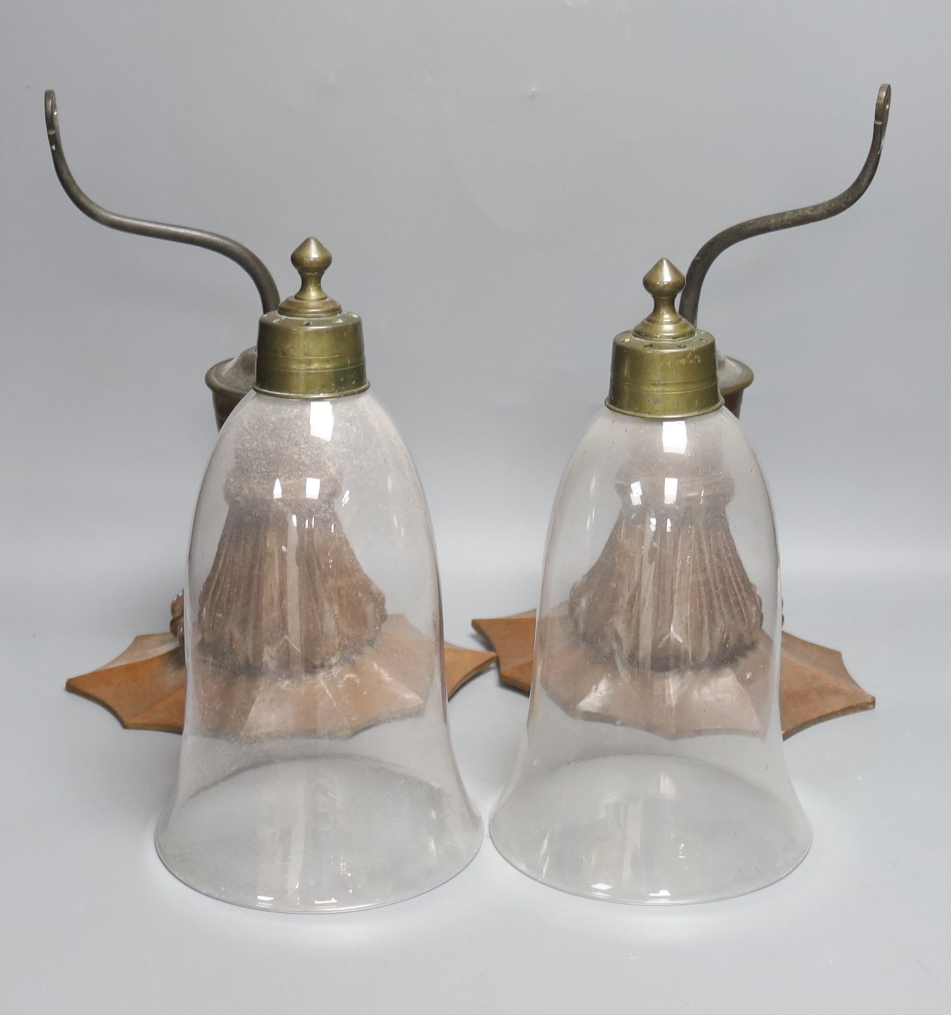 A pair of early 20th century decorative carved oand brass wall lights with glass storm shades